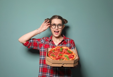 Attractive young woman with delicious pizza on color background