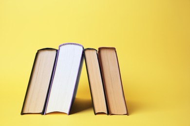 Photo of Collection of hardcover books on yellow background, space for text