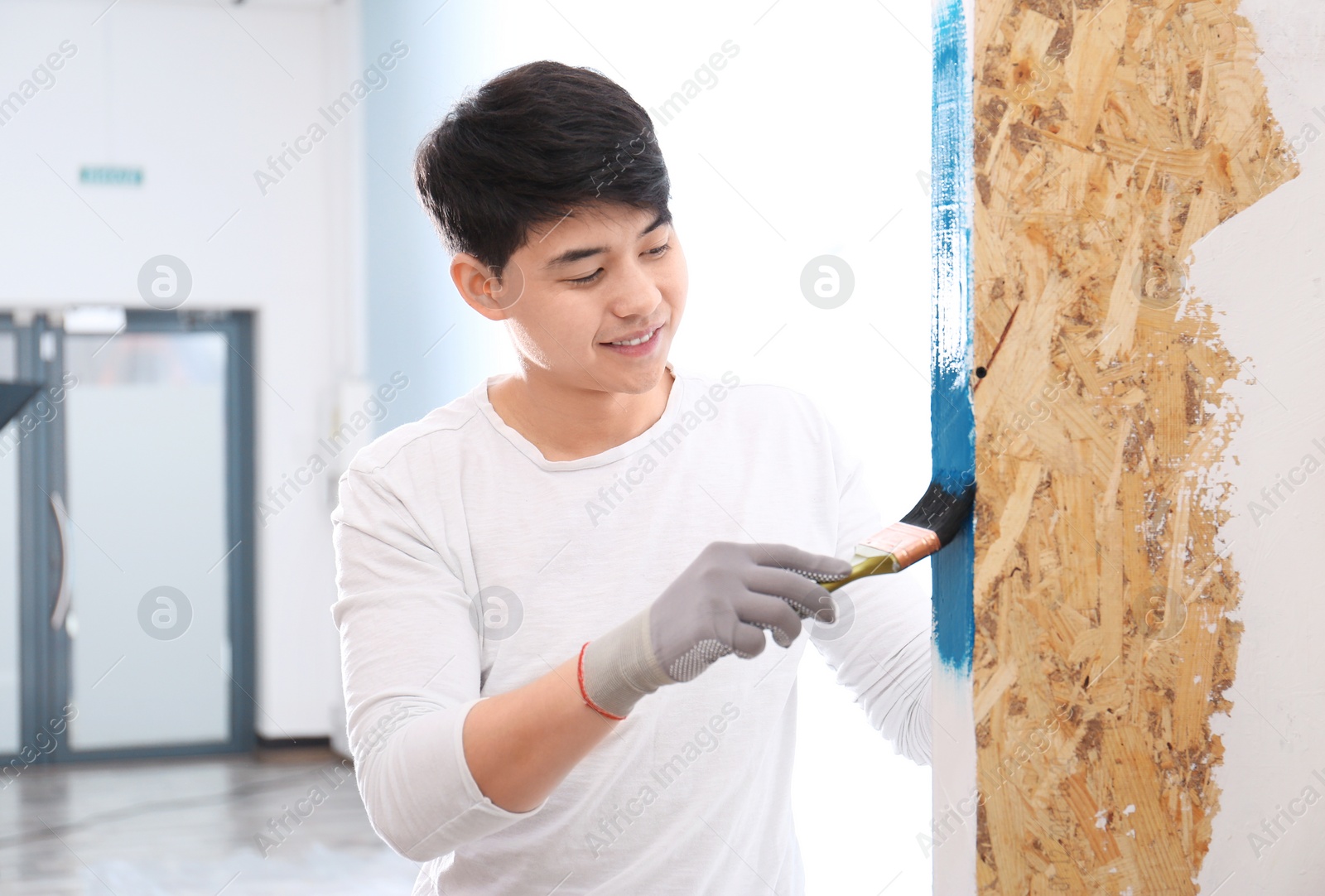 Photo of Male decorator painting wall with brush indoors