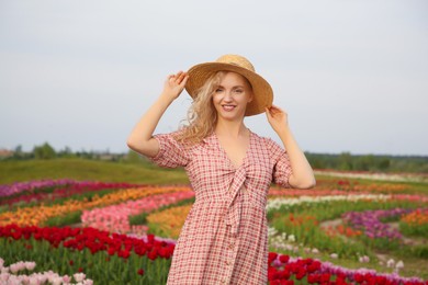 Happy woman in beautiful tulip field outdoors