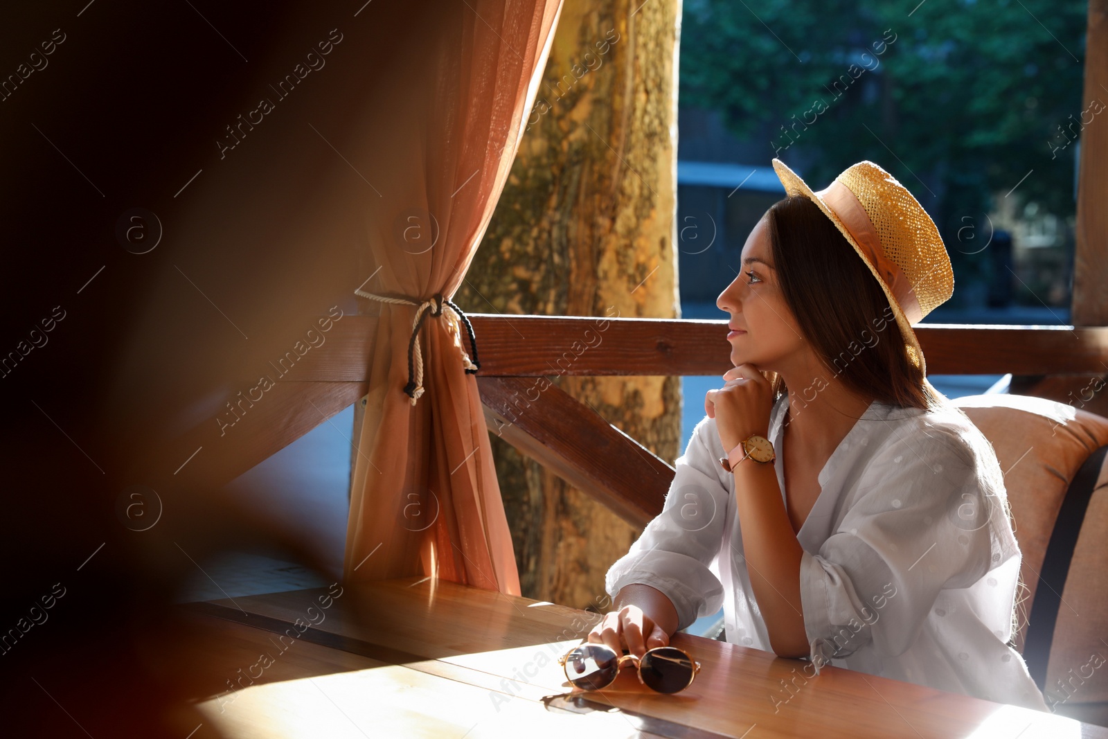 Photo of Beautiful young woman resting at table in outdoor cafe