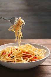 Photo of Eating delicious pasta with tomatoes and parmesan cheese at wooden table, closeup