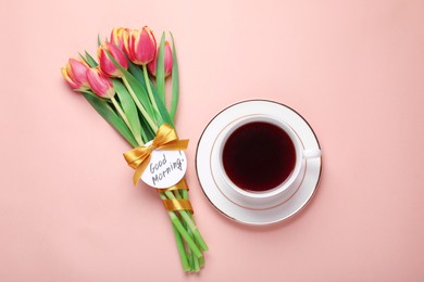 Cup of coffee, beautiful tulips and card with text Good Morning on beige background, flat lay