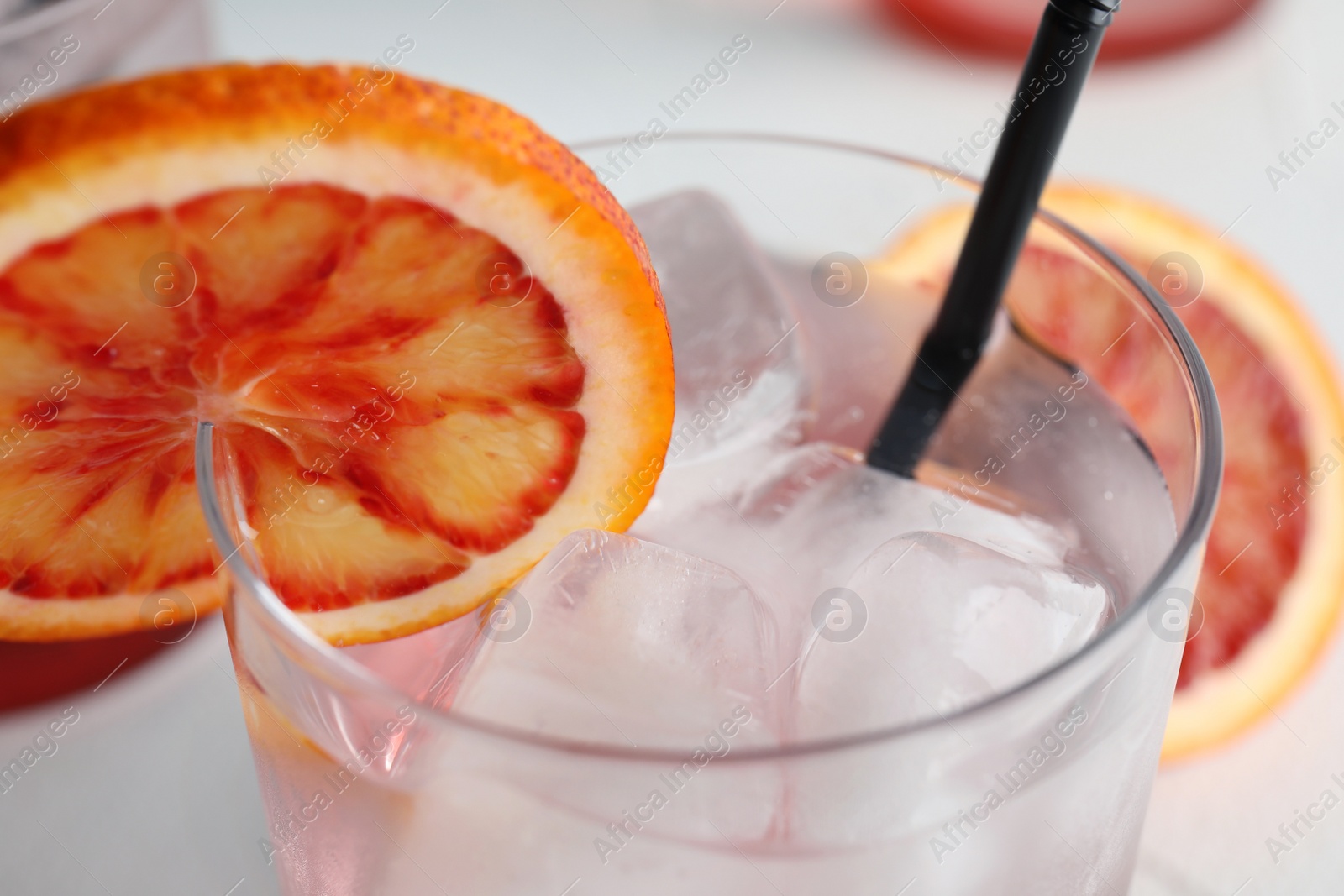 Photo of Glass of drink with ice cubes and orange, closeup