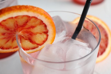 Photo of Glass of drink with ice cubes and orange, closeup