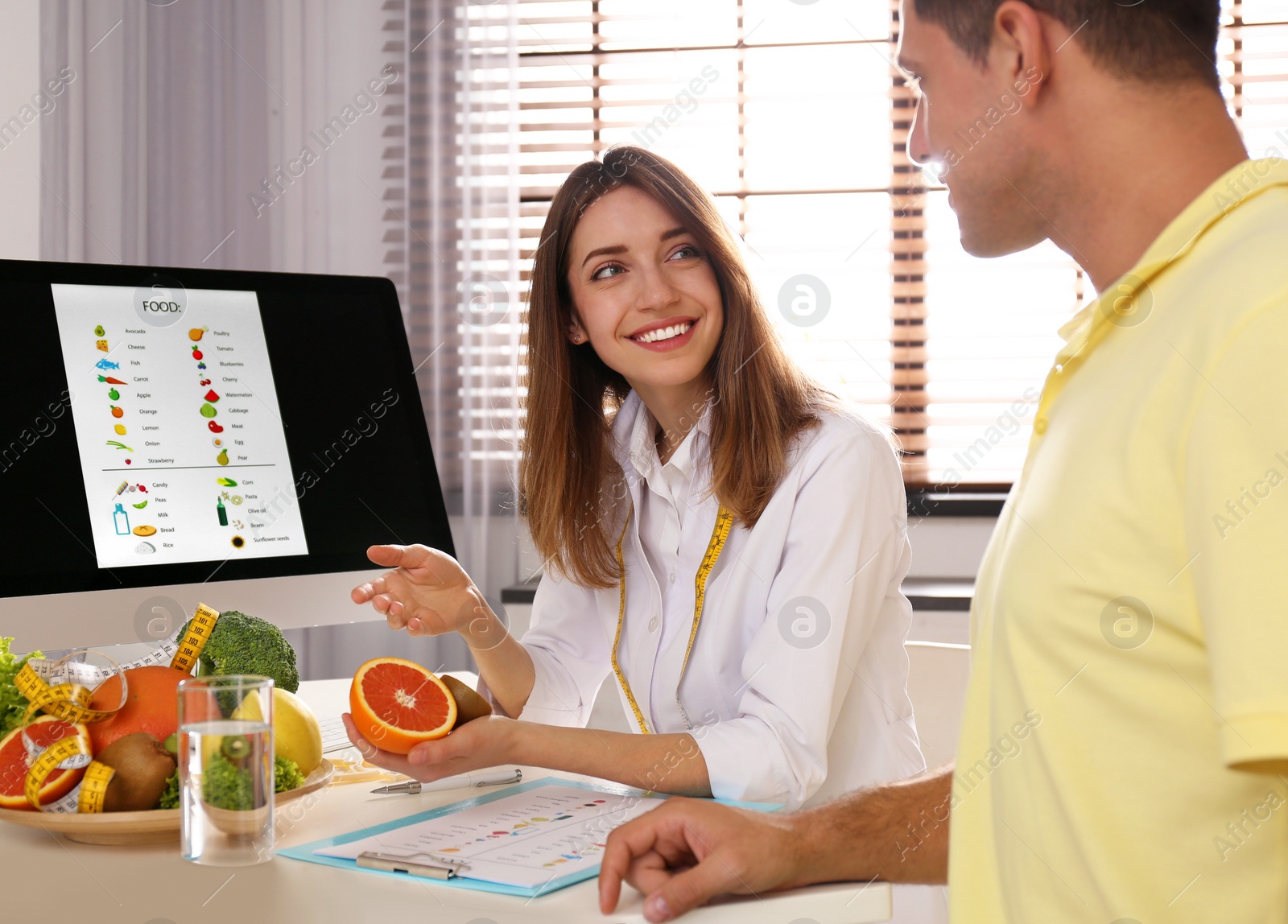 Photo of Young nutritionist consulting patient at table in clinic