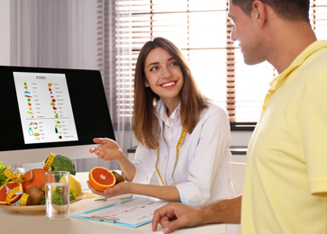 Photo of Young nutritionist consulting patient at table in clinic