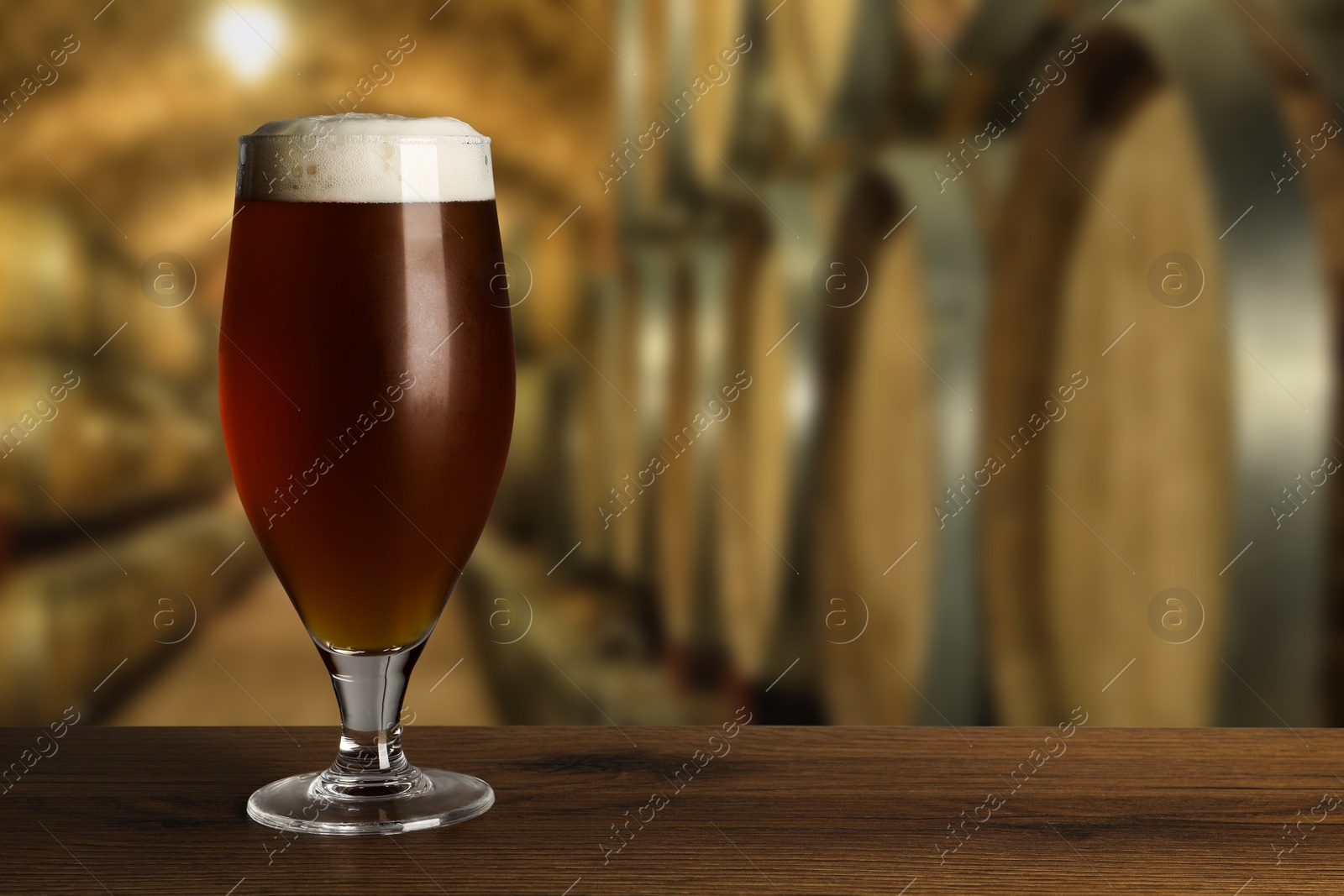 Image of Glass with fresh beer on wooden table in cellar, space for text