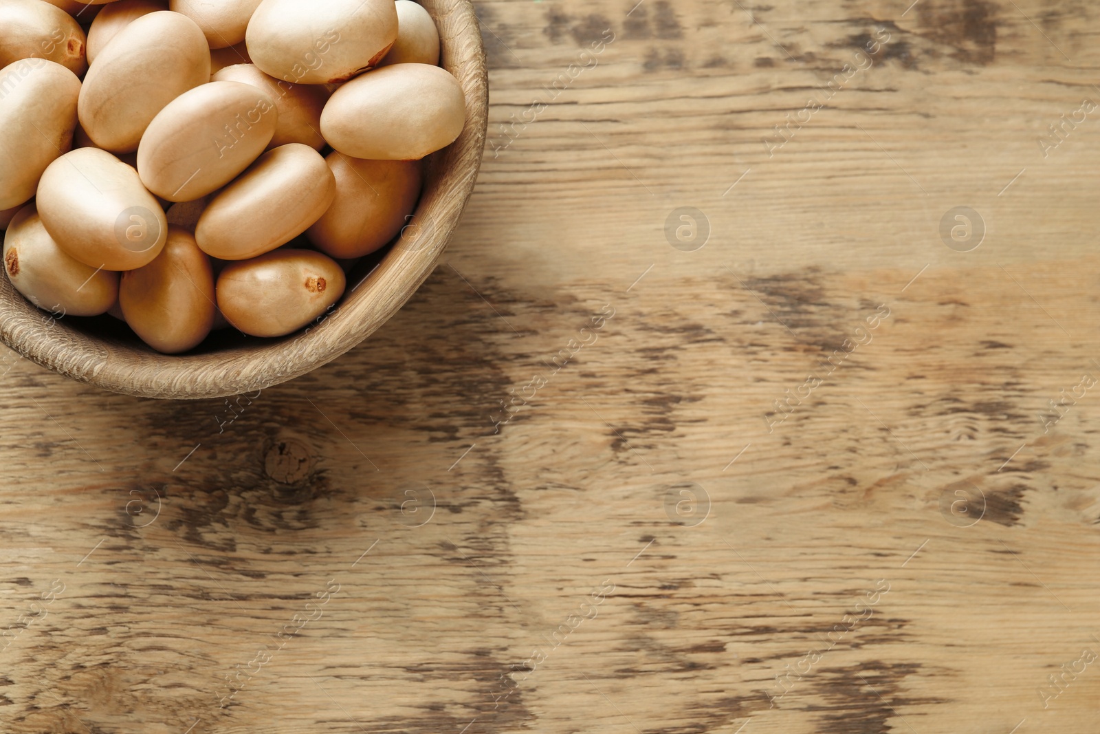 Photo of Raw jackfruit seeds on wooden table, top view. Space for text