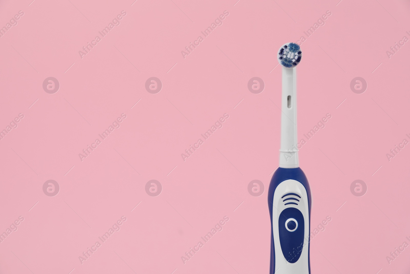 Photo of Electric toothbrush on pink background, space for text