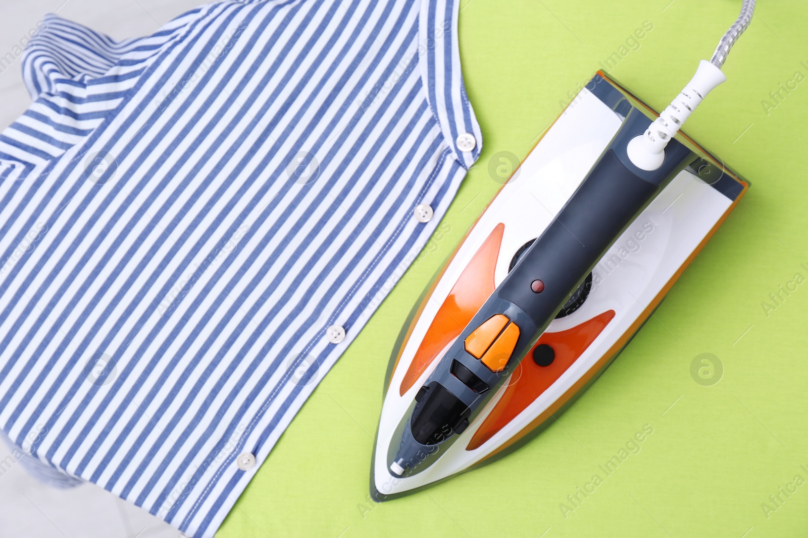 Photo of Modern electric iron and shirt on color background, top view with space for text. Laundry day