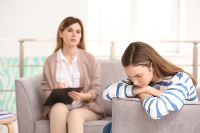 Photo of Young female psychologist working with teenage girl in office