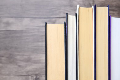 Collection of different books near wooden wall, closeup. Space for text