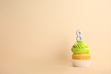 Birthday cupcake with number eight candle on beige background, space for text