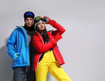 Photo of Couple wearing stylish winter sport clothes on light grey background. Space for text