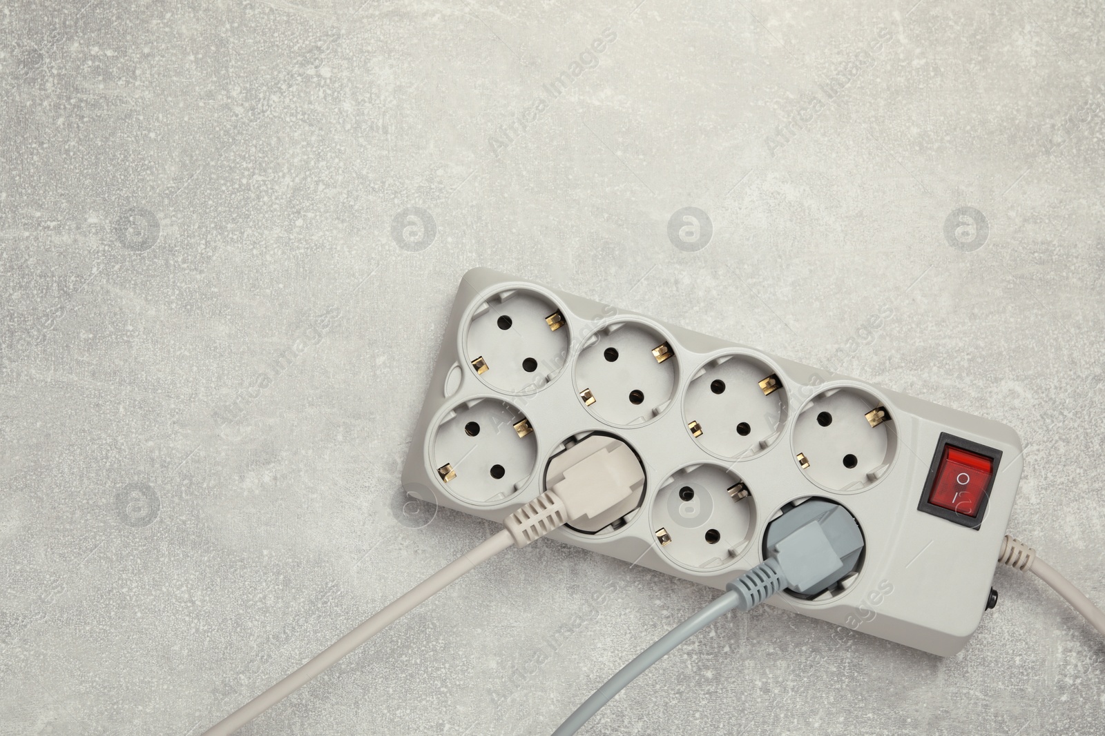 Photo of Power strip with extension cord on light grey table, top view. Space for text