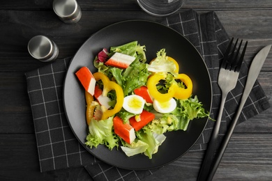 Photo of Salad with crab sticks and lettuce served on black wooden table, flat lay