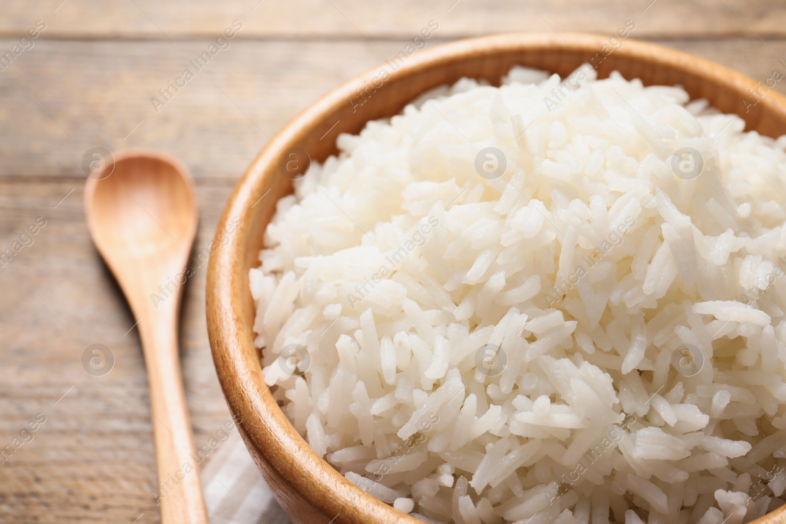 Photo of Bowl of delicious rice on wooden table, closeup
