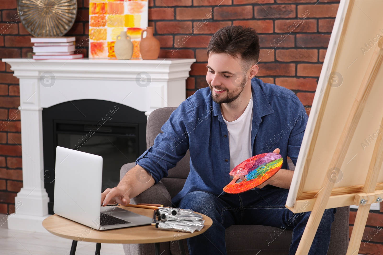 Photo of Happy man learning to draw with online course on laptop at home. Time for hobby