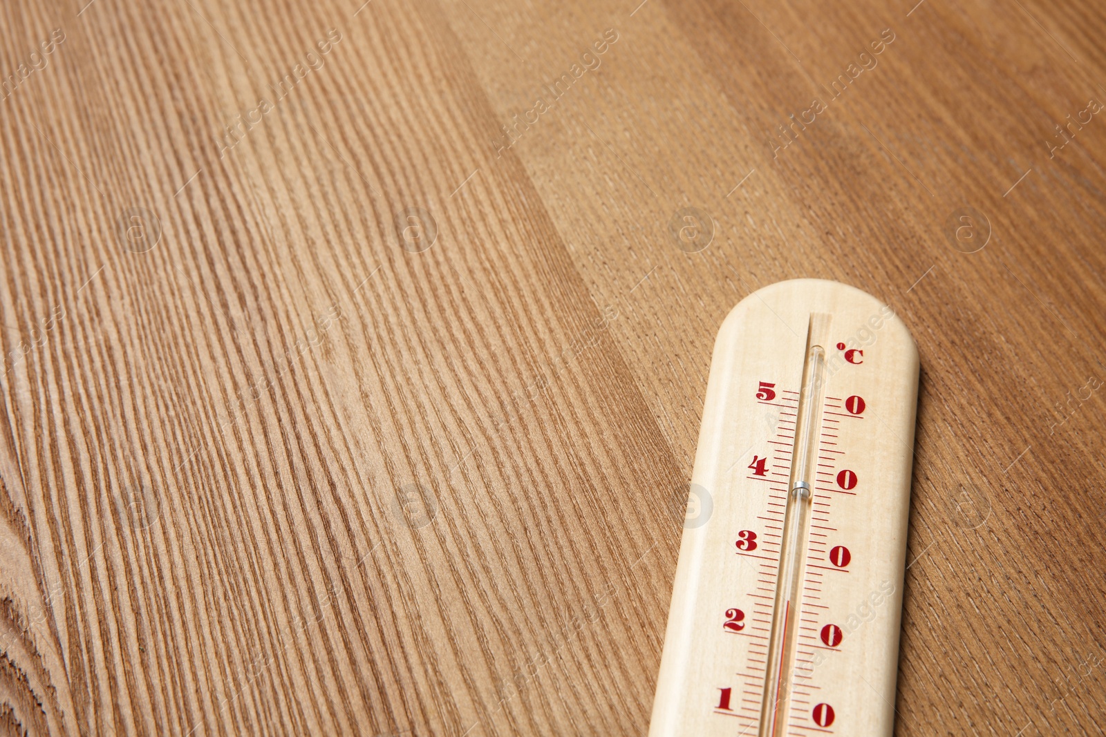 Photo of Weather thermometer on wooden table, closeup. Space for text