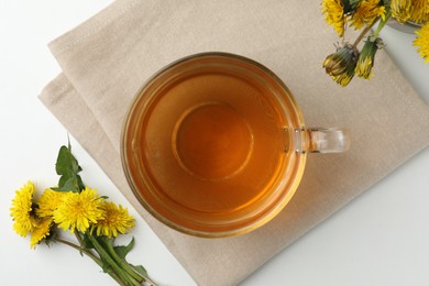 Photo of Delicious fresh tea and dandelion flowers on white table, flat lay