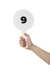 Photo of Woman holding auction paddle with number 9 on white background, closeup