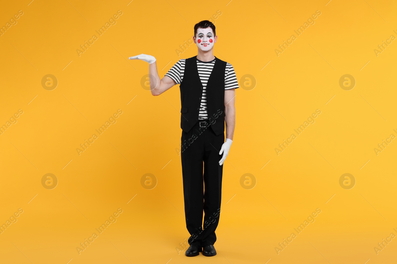 Photo of Funny mime artist posing on orange background