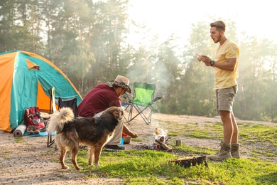Photo of People cooking on bonfire near camping tent in wilderness