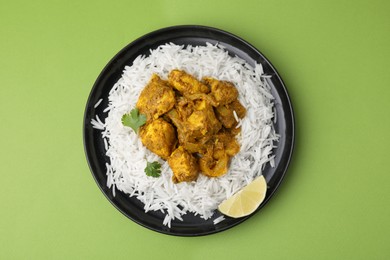 Photo of Delicious chicken curry with rice on green background, top view