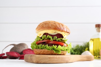 Delicious vegetarian burger and ingredients on white wooden table