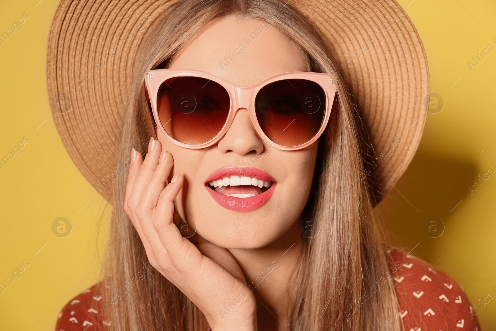 Photo of Young woman wearing stylish sunglasses and hat on yellow background