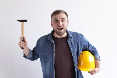 Photo of Happy young working man with hammer and hardhat on white background