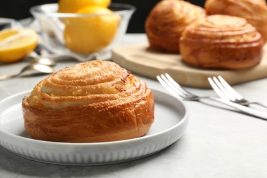 Photo of Plate with tasty bun on stone table, space for text. Fresh from oven