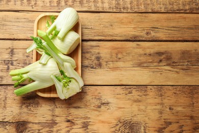 Photo of Fresh raw fennel bulbs on wooden table, top view. Space for text