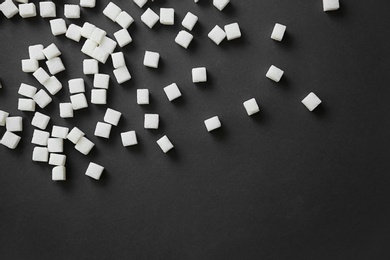 Photo of Refined sugar cubes on dark background, top view
