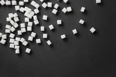 Refined sugar cubes on dark background, top view