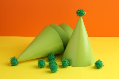 Party hats on yellow table against orange background