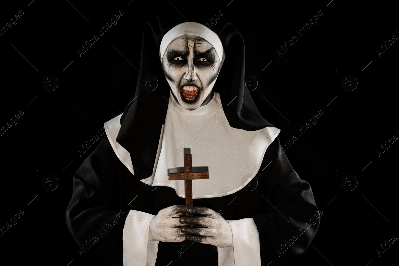 Photo of Scary devilish nun with cross on black background. Halloween party look