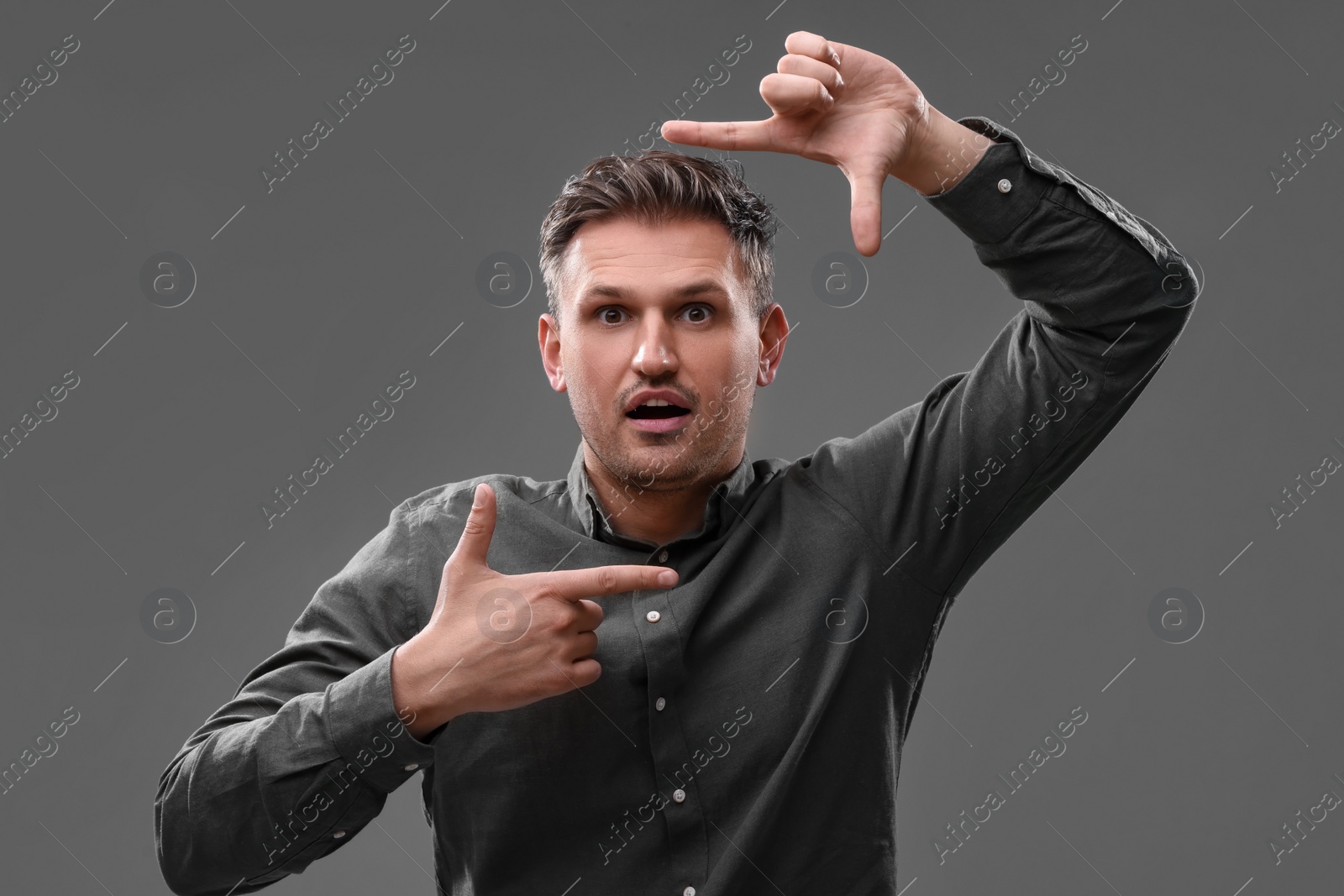 Photo of Casting call. Emotional man showing frame gesture on grey background