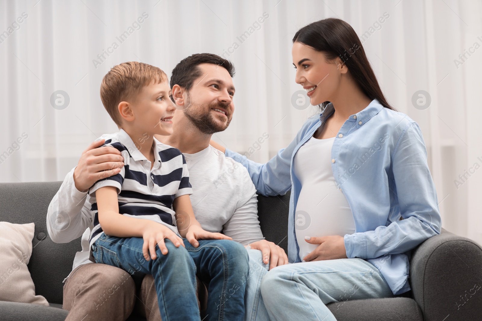 Photo of Happy pregnant woman spending time with her son and husband at home