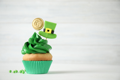 Decorated cupcake on white wooden table, space for text. St. Patrick's Day celebration