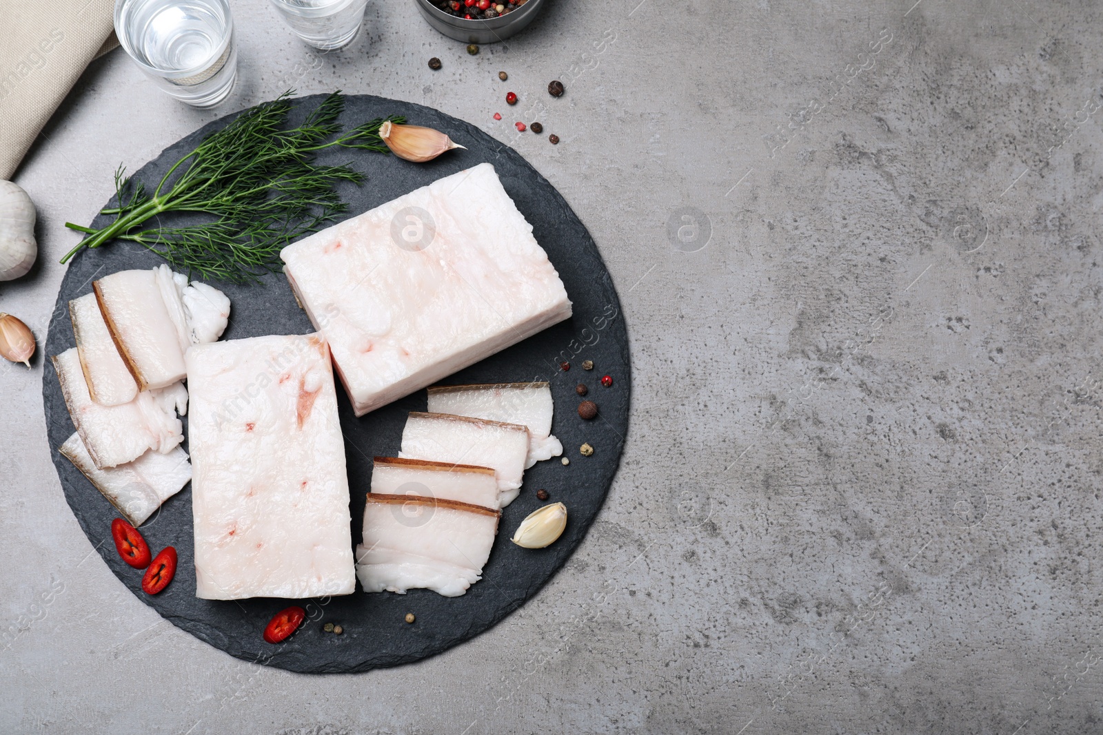 Photo of Pork fatback with spices served on grey table, flat lay. Space for text