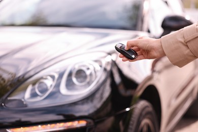 Woman holding car flip key near her vehicle outdoors, closeup