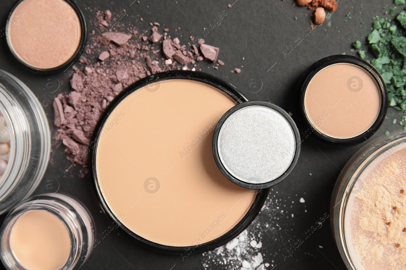 Photo of Flat lay composition with various makeup face powders on dark background