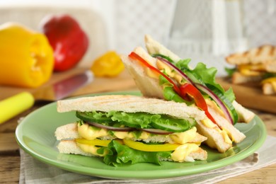 Photo of Green plate with tasty sandwiches on table
