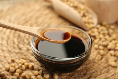 Taking soy sauce with spoon from bowl at table, closeup