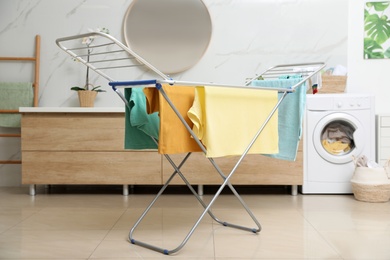 Clean laundry hanging on drying rack in bathroom