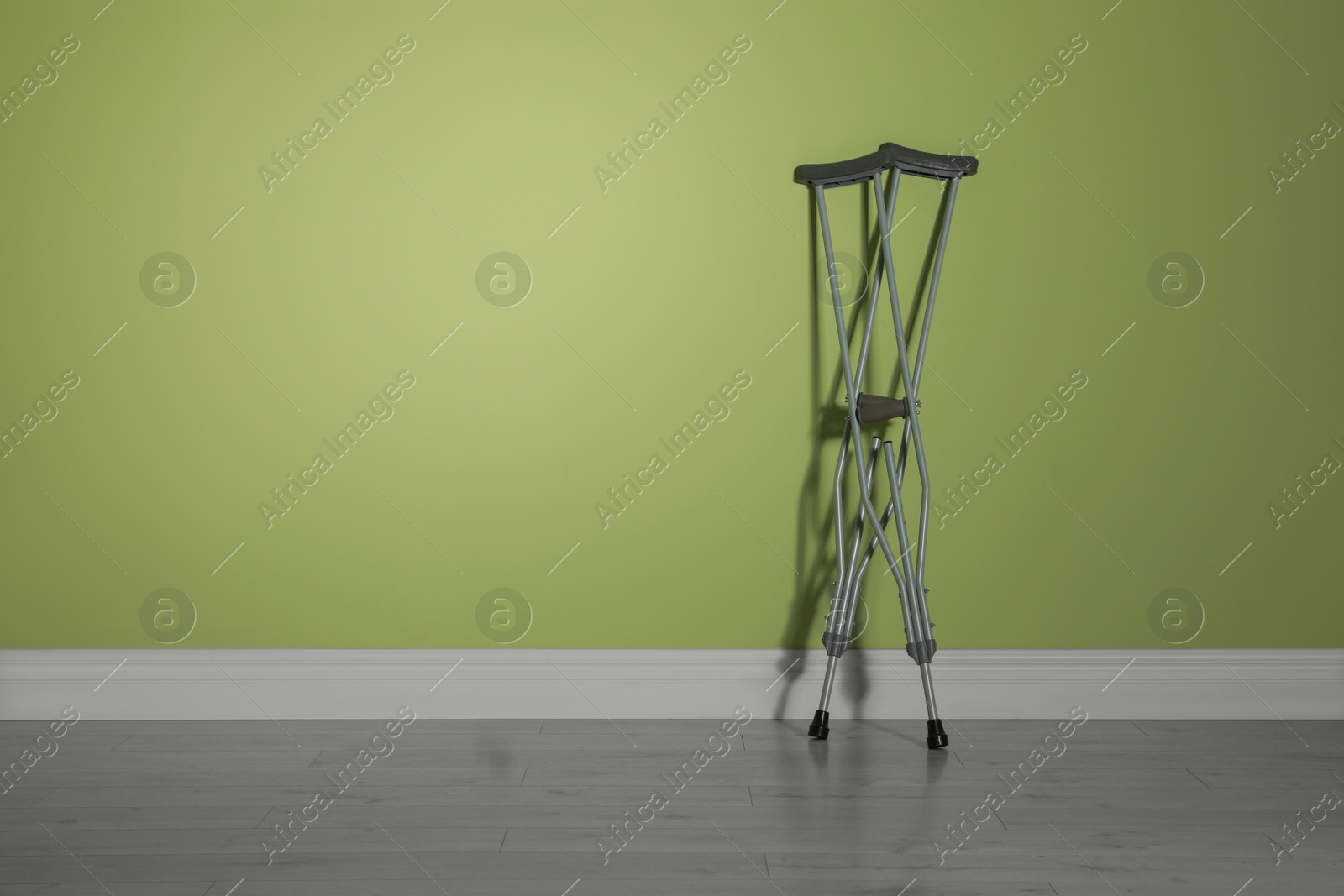 Photo of Pair of axillary crutches near light green wall. Space for text