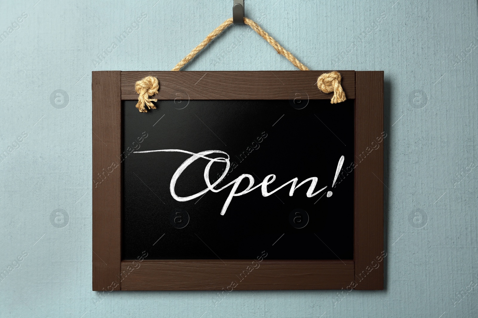 Image of Small chalk board with word Open on light blue wall