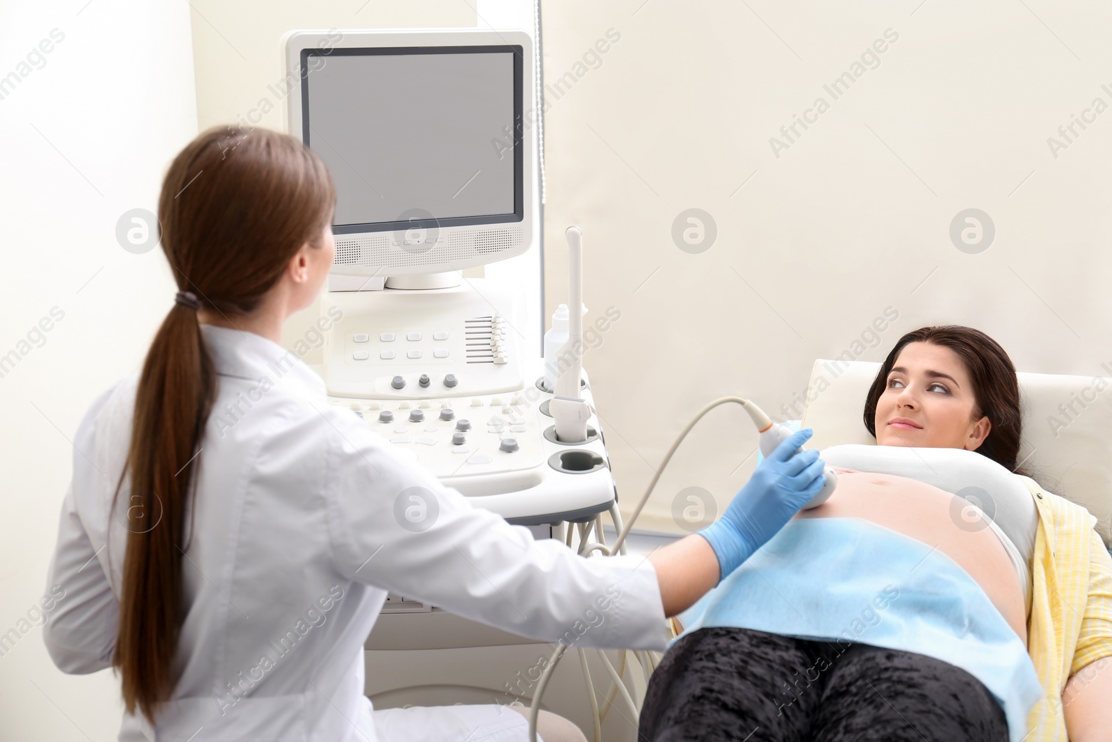 Photo of Young pregnant woman undergoing ultrasound scan in clinic